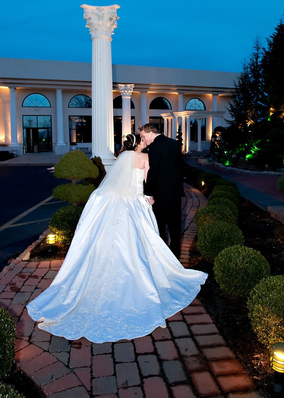 A bride and groom kissing in front of a building with columns