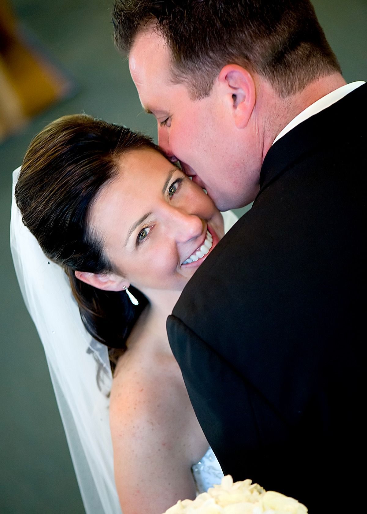 A man kissing a woman on the cheek on their wedding day