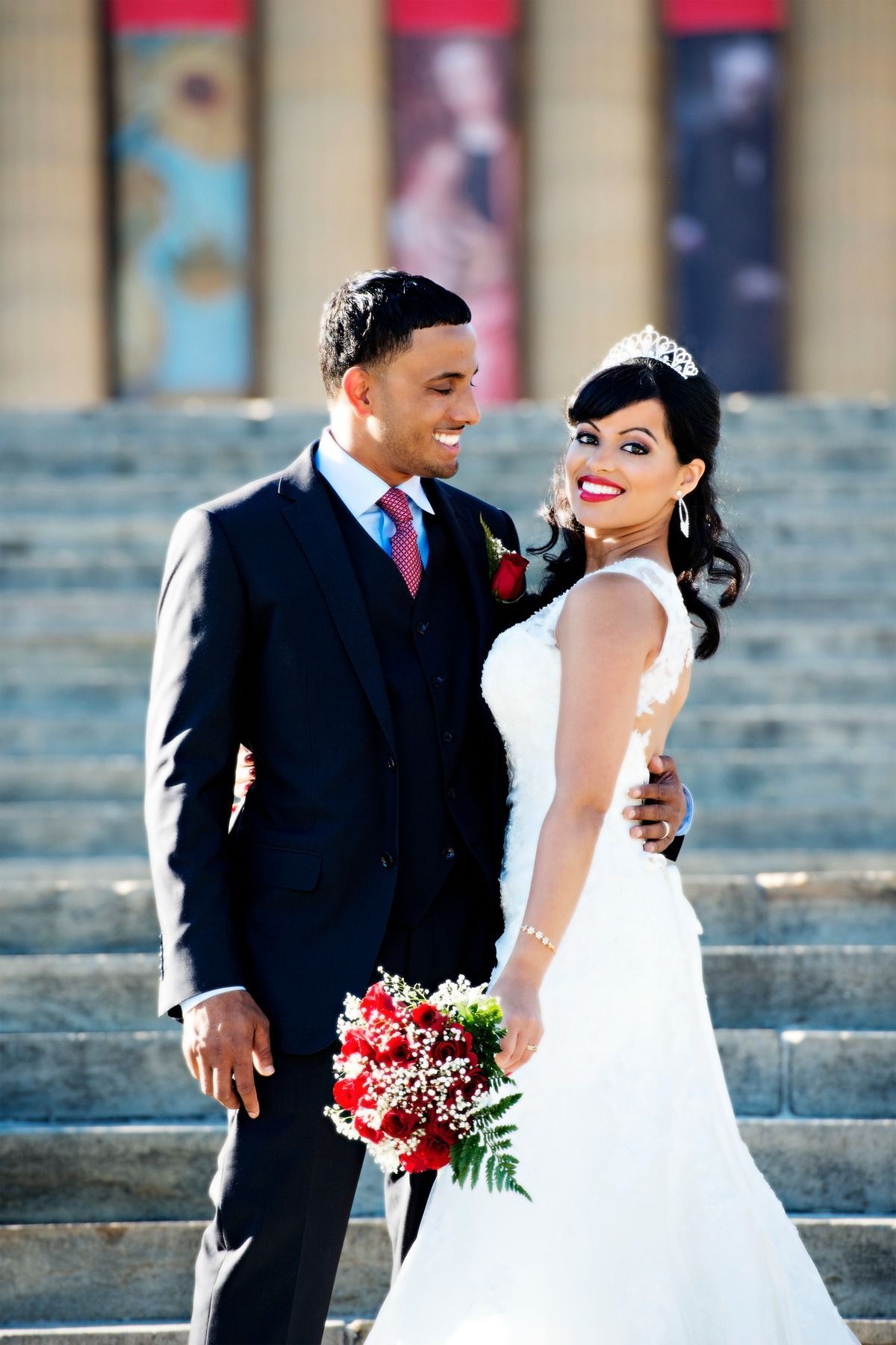 A bride and groom are posing for a picture on a set of stairs.