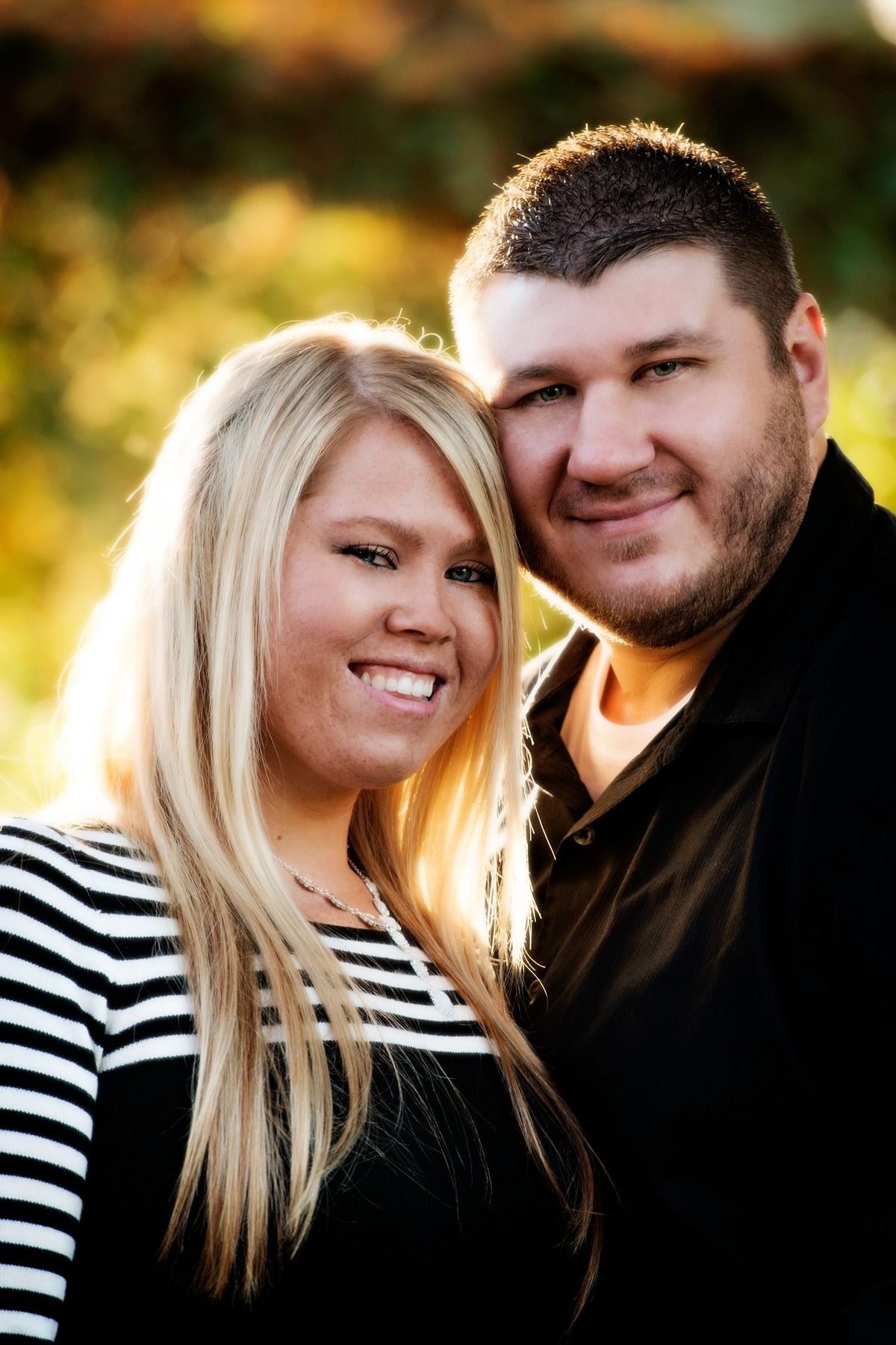 A man and a woman are posing for a picture and smiling for the camera.