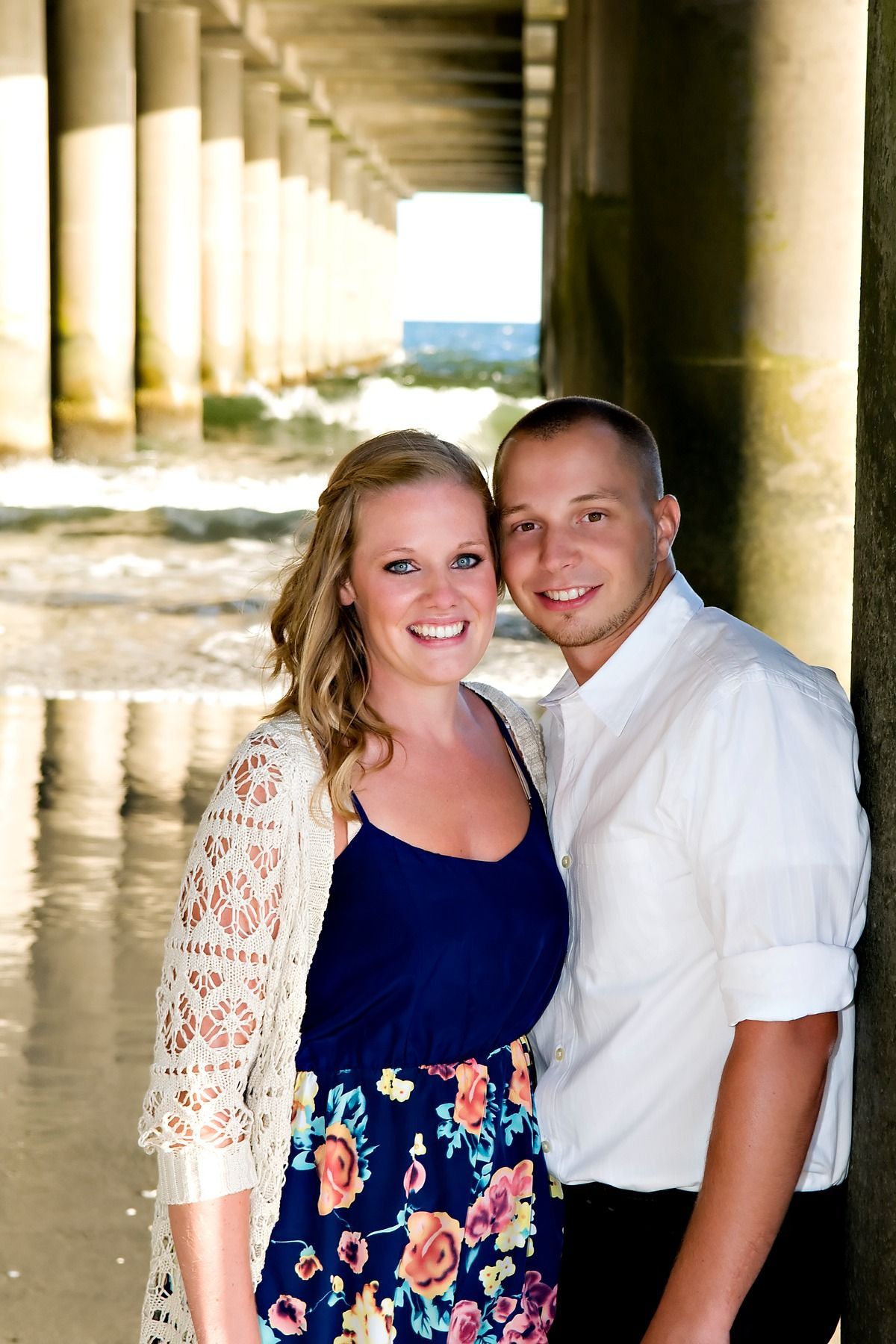 A man and a woman are posing for a picture under a bridge.