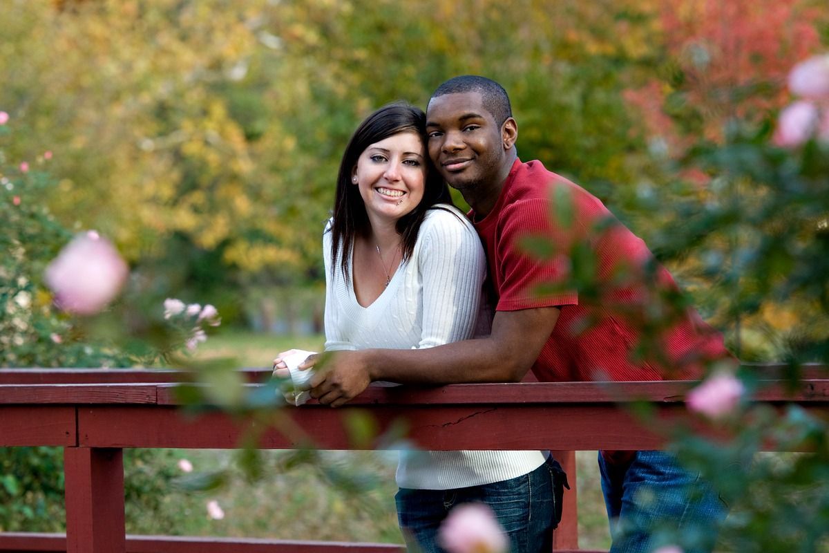 A man and a woman are standing next to each other on a bridge.