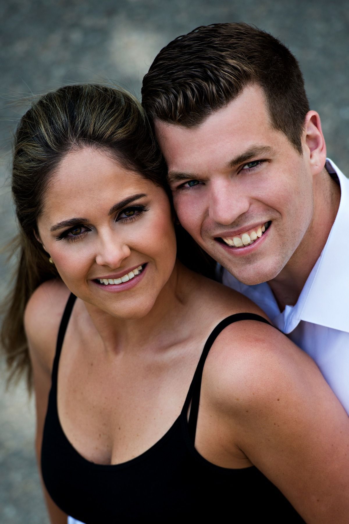 A man and a woman are posing for a picture and smiling for the camera