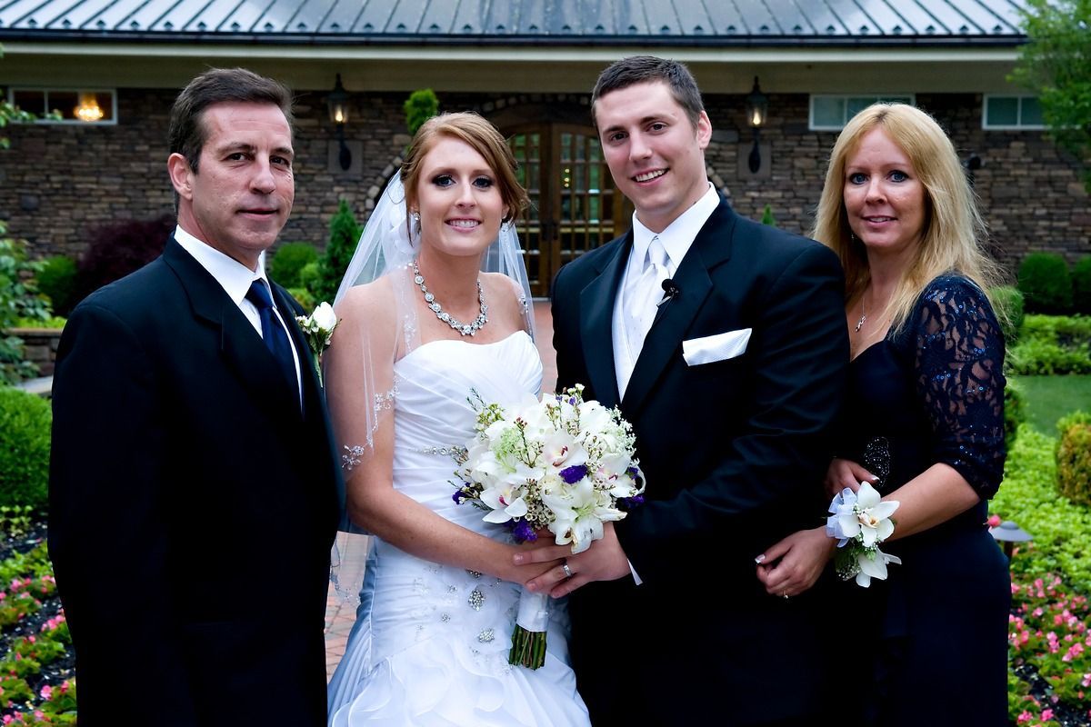 A bride and groom pose for a picture with their parents