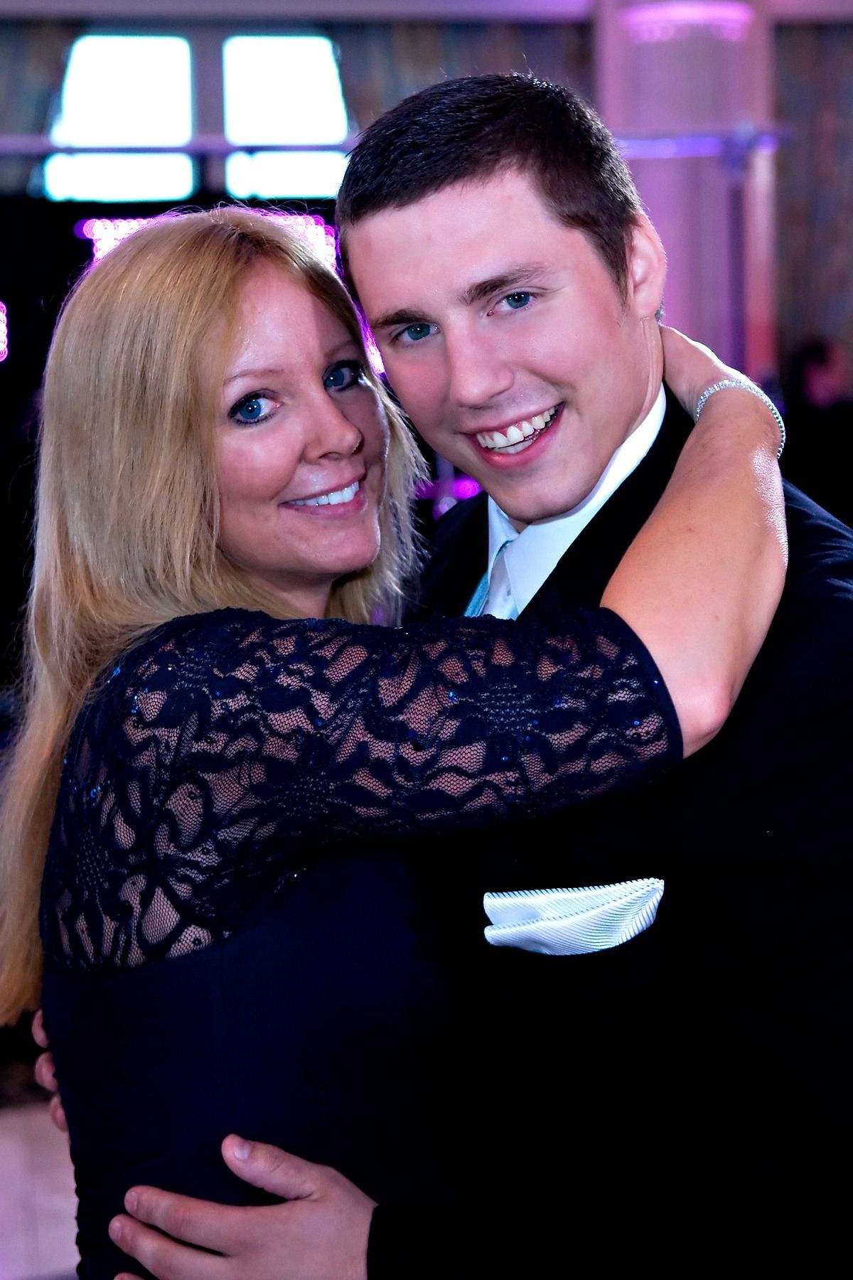 A man and a woman are hugging each other and smiling for the camera.