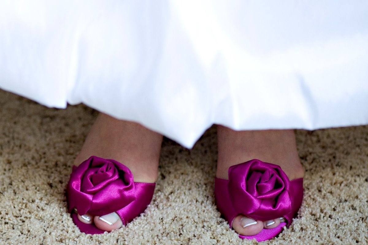 A woman wearing a white dress and purple shoes with roses on them.