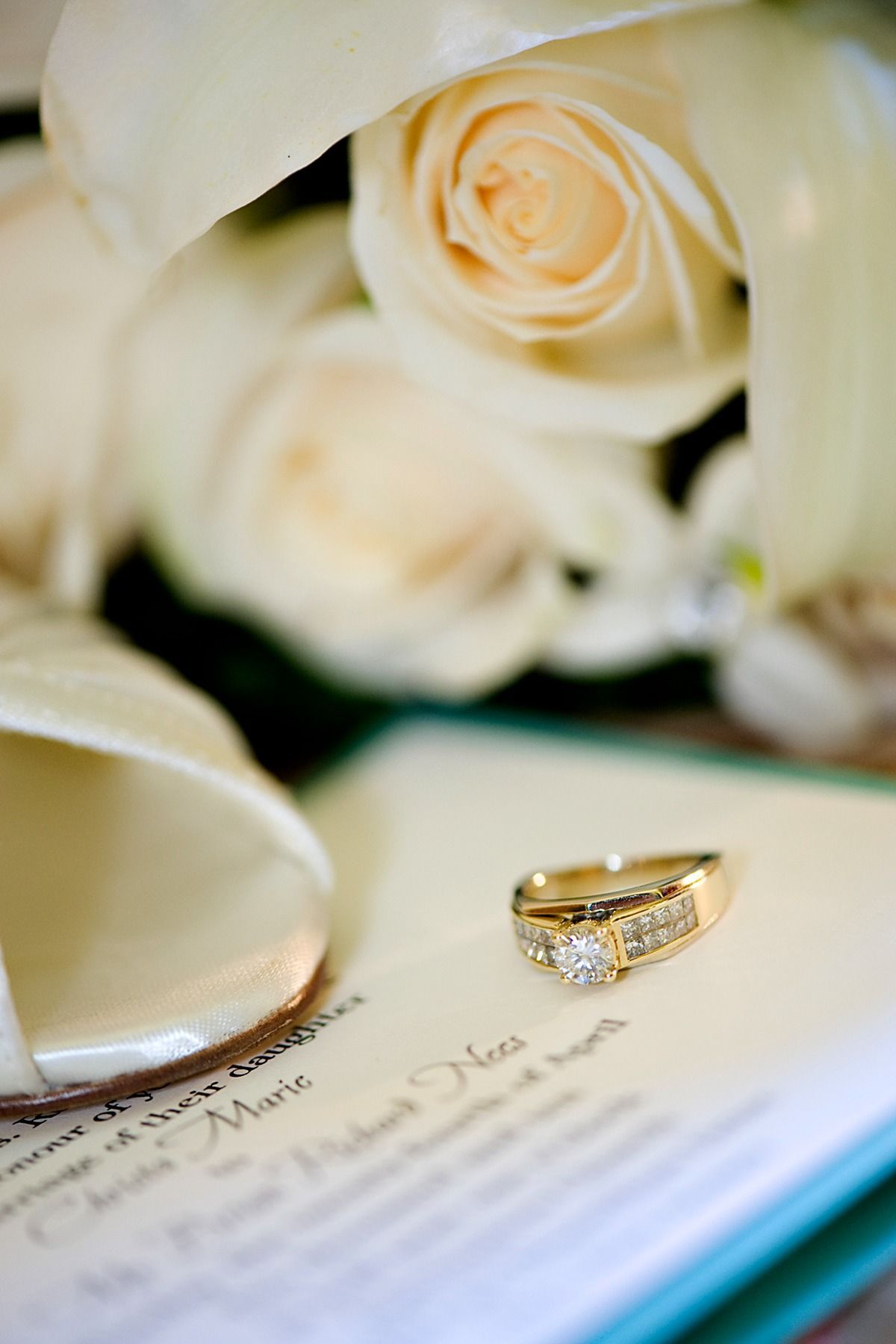 A wedding ring is sitting on top of a wedding invitation