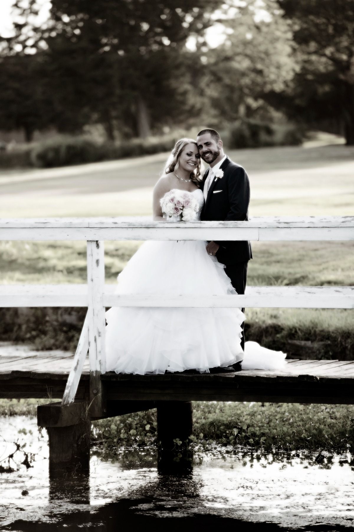 A bride and groom are posing for a picture on a bridge