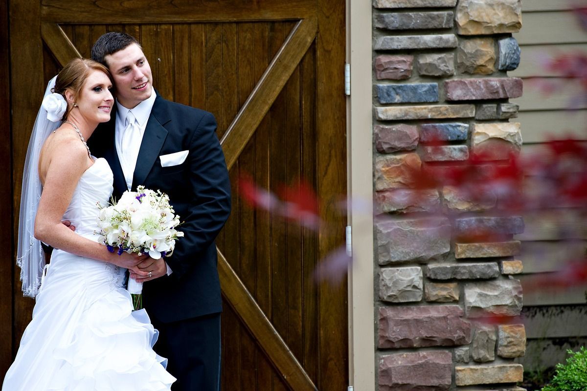 A bride and groom are posing for a picture in front of a wooden door.