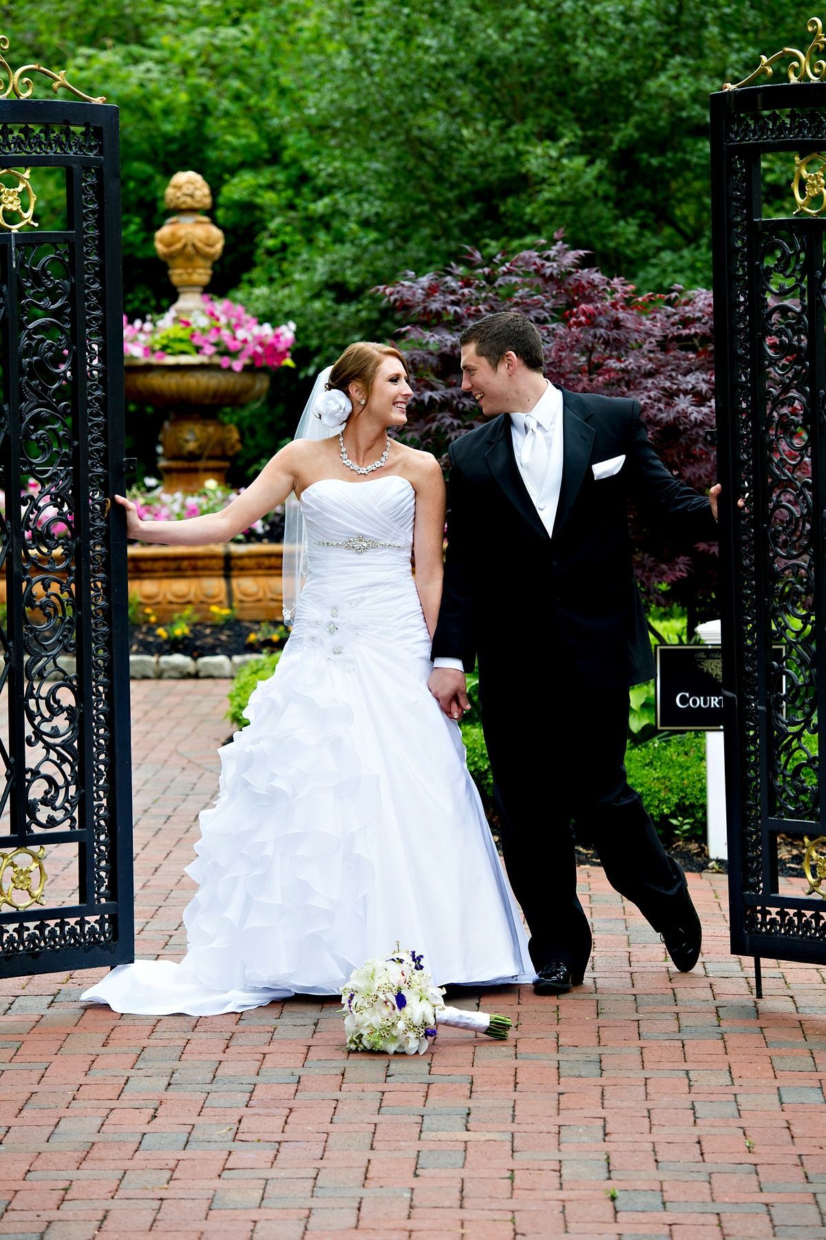 A bride and groom are posing for a picture in front of a gate