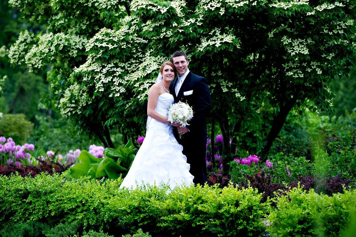 A bride and groom are posing for a picture in a garden.