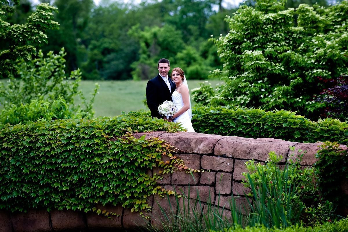 A bride and groom are posing for a picture on a bridge.