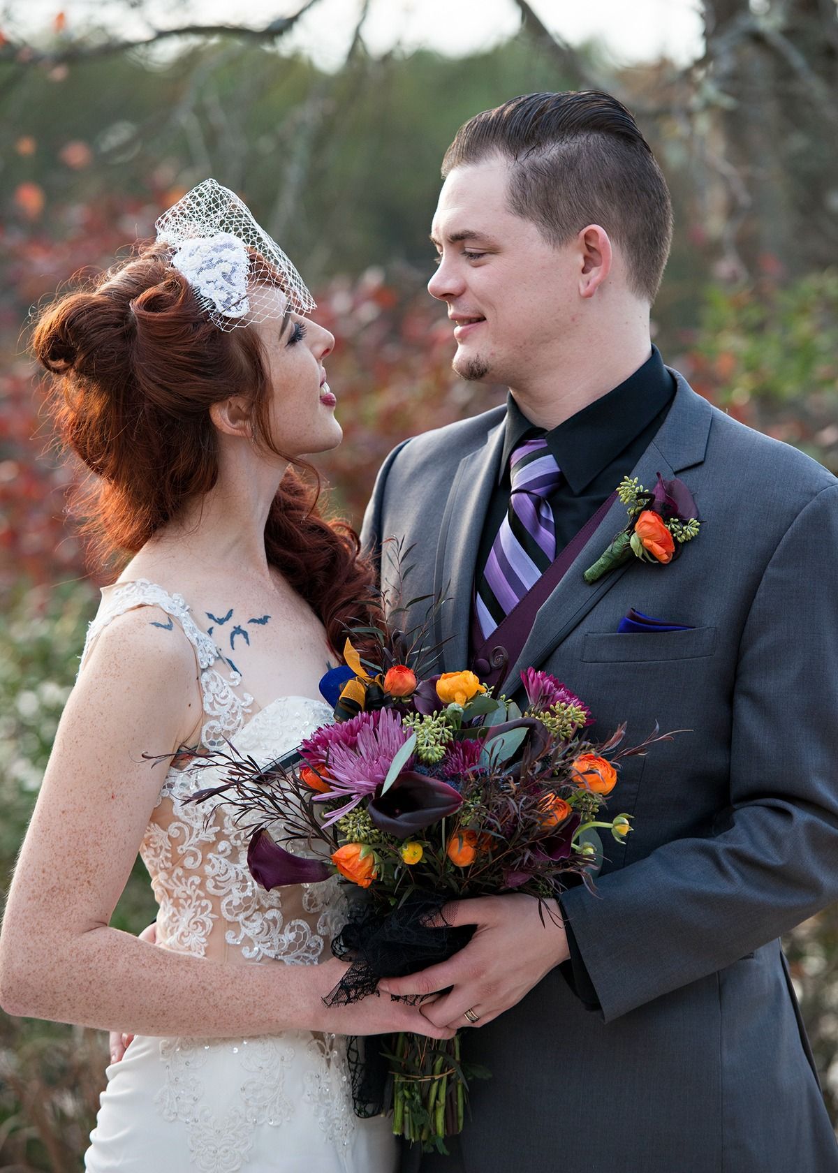 A bride and groom are posing for a picture while the bride is holding a bouquet of flowers.