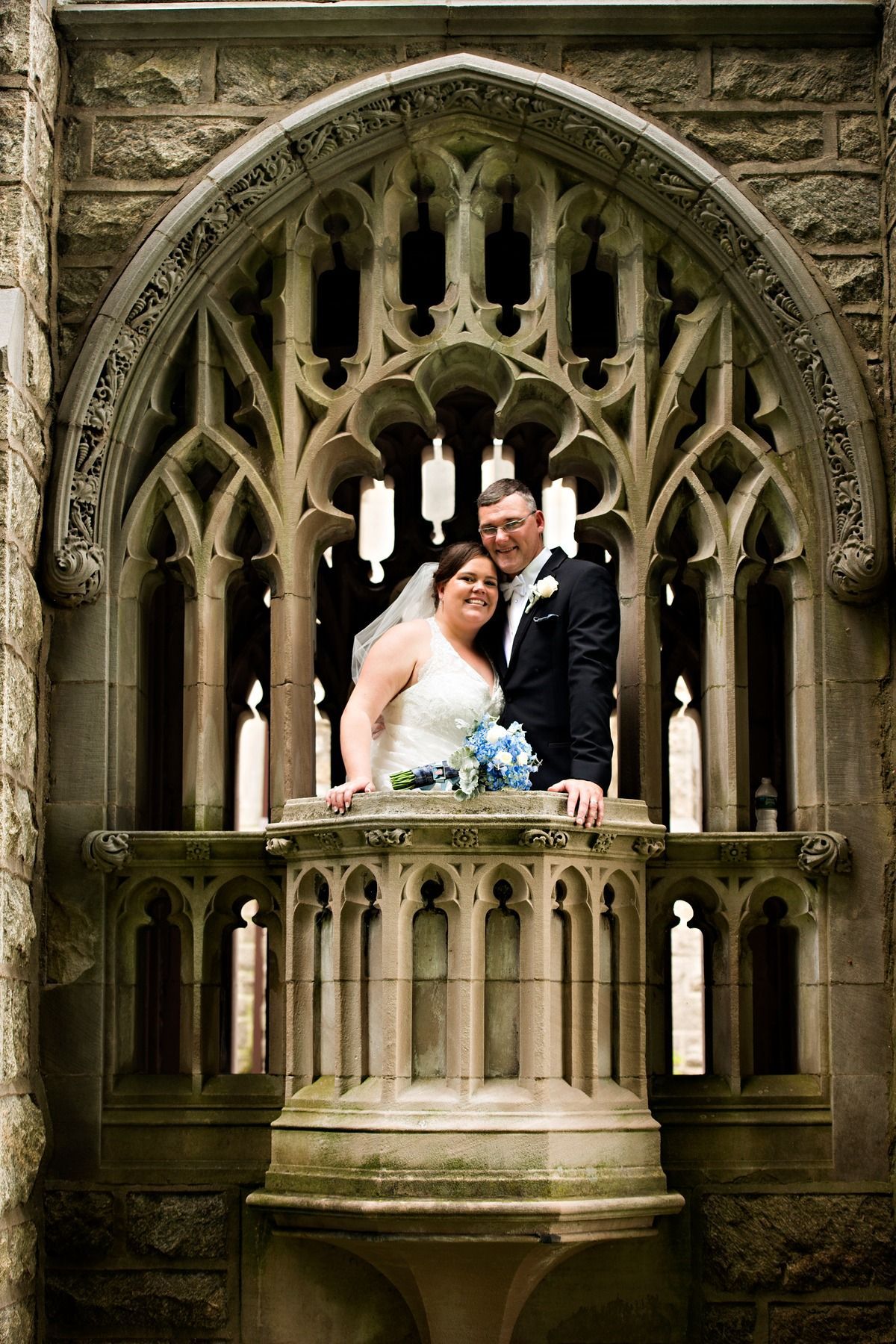 A bride and groom are posing for a picture in front of a window.