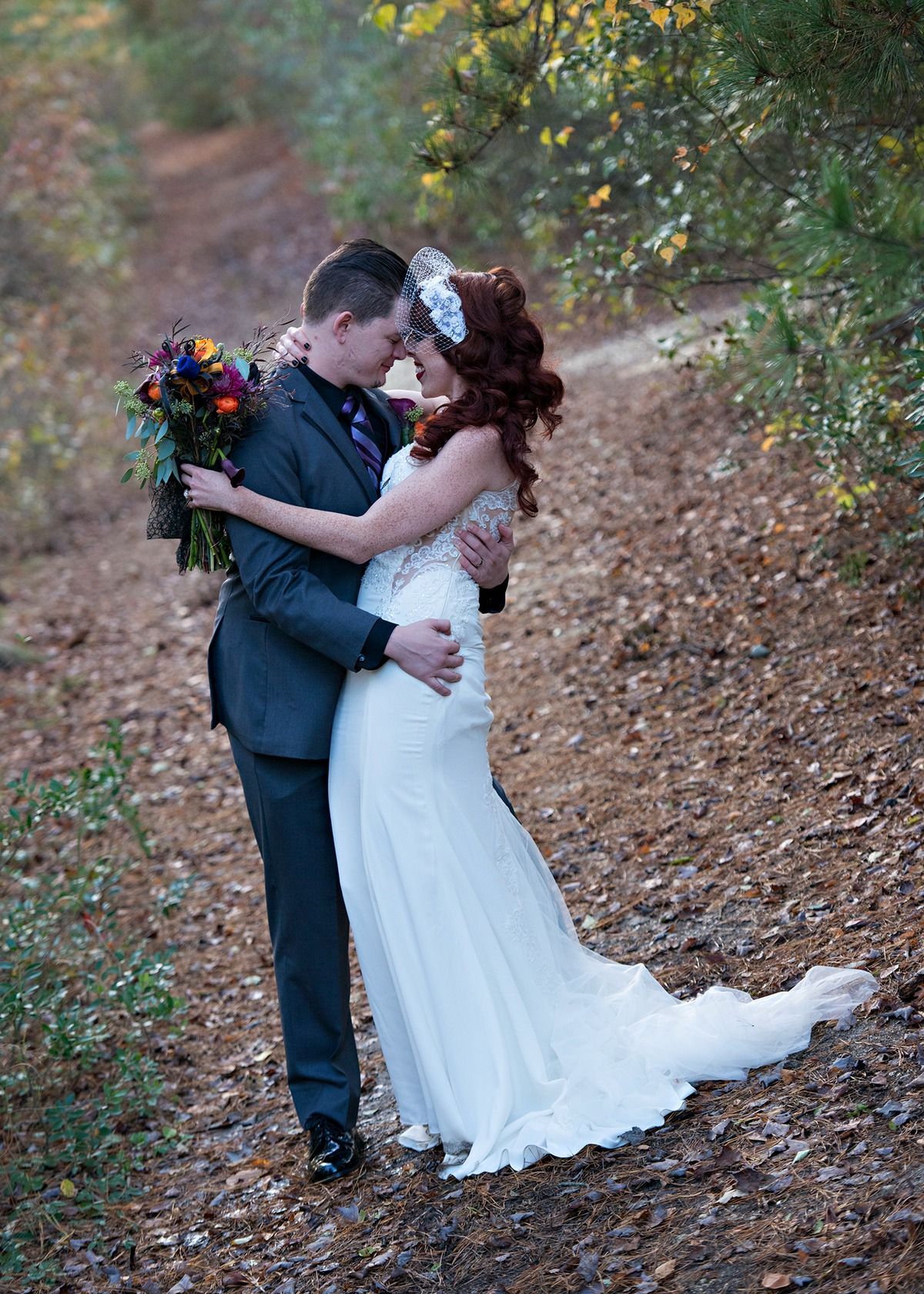 A bride and groom are kissing in the woods.