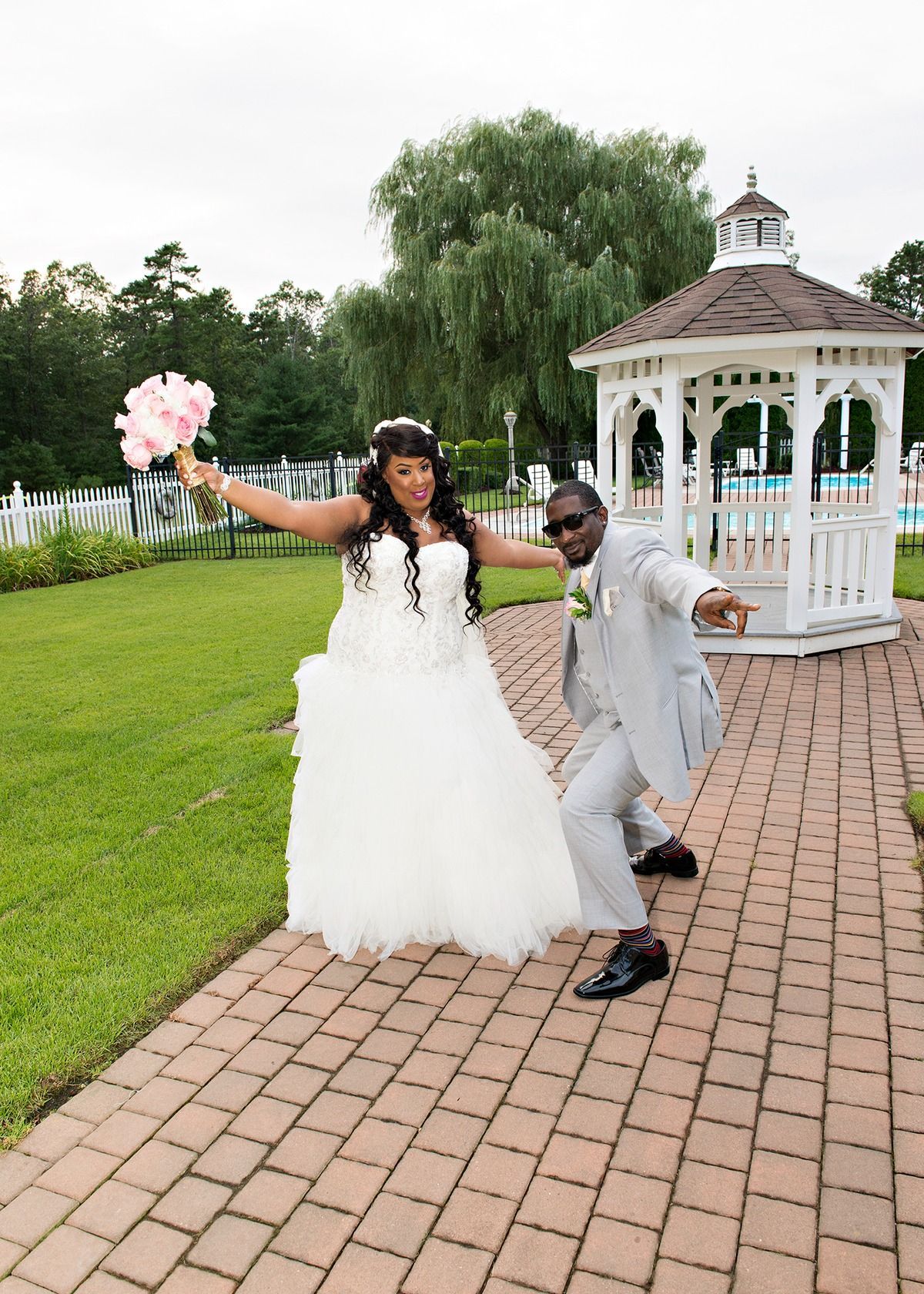 A bride and groom are posing for a picture in front of a gazebo.