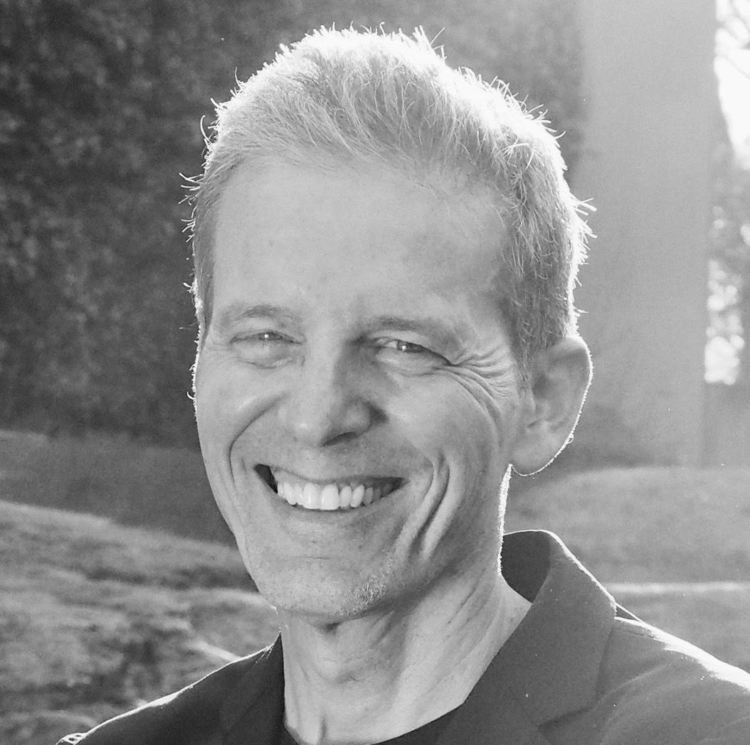 A man is smiling in a black and white photo