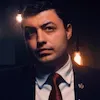 A man in a suit and tie is standing in a dark room.