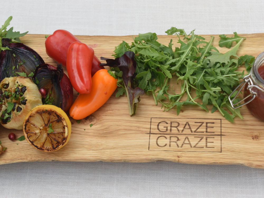 A wooden grazing board filled with vegetables and a jar of sauce.