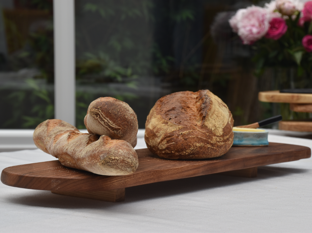 Two loaves of bread are sitting on a wooden grazing board.