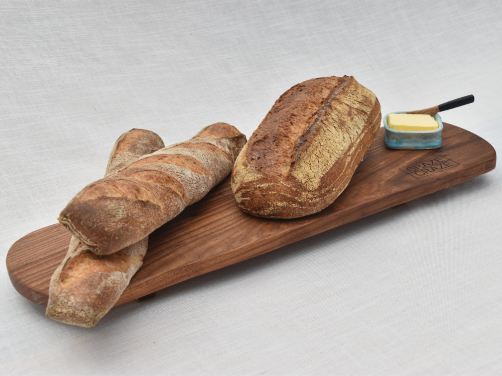 A wooden grazing board with bread and butter on it