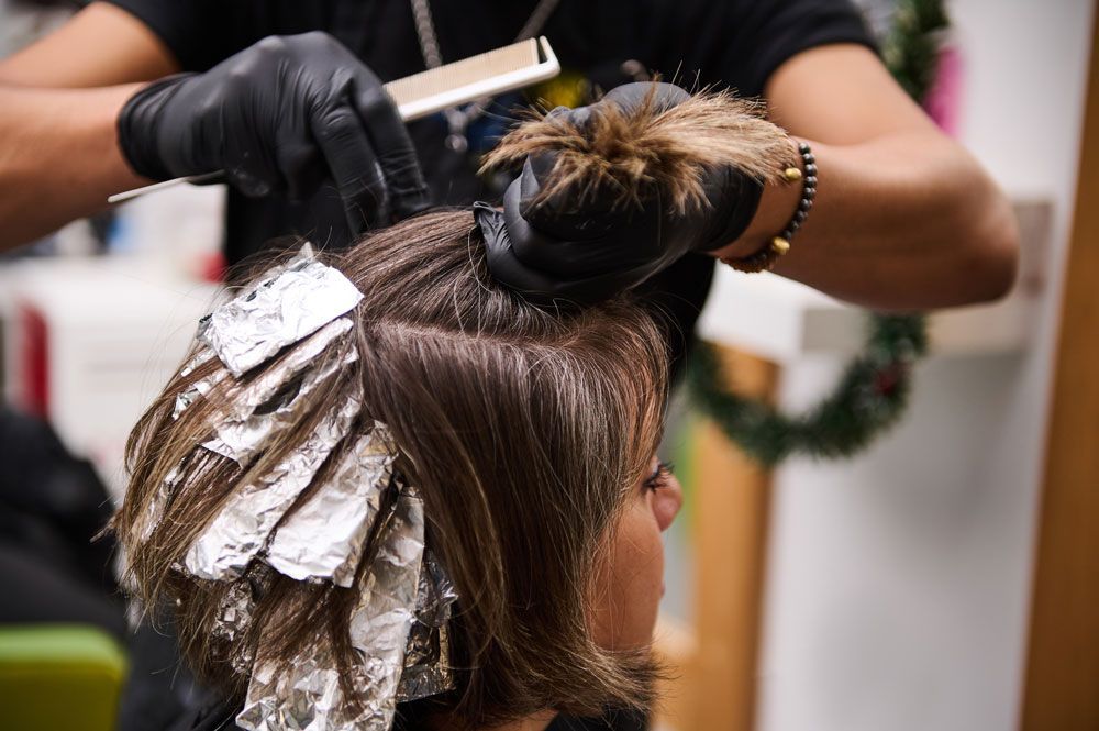 A woman is getting her hair dyed by a hairdresser in a salon.