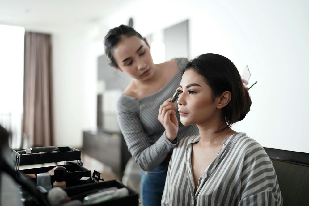 A woman is getting her makeup done by a makeup artist.