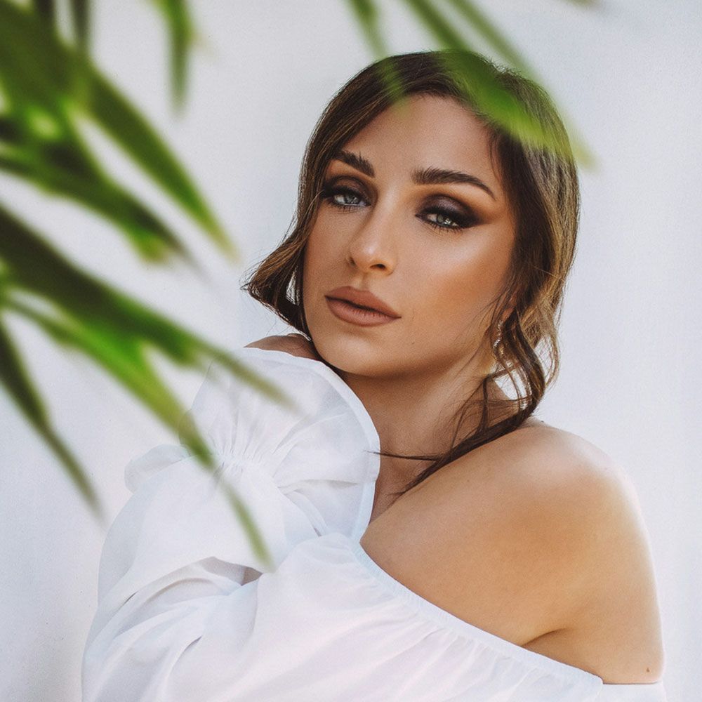 The woman is wearing a white off the shoulder top