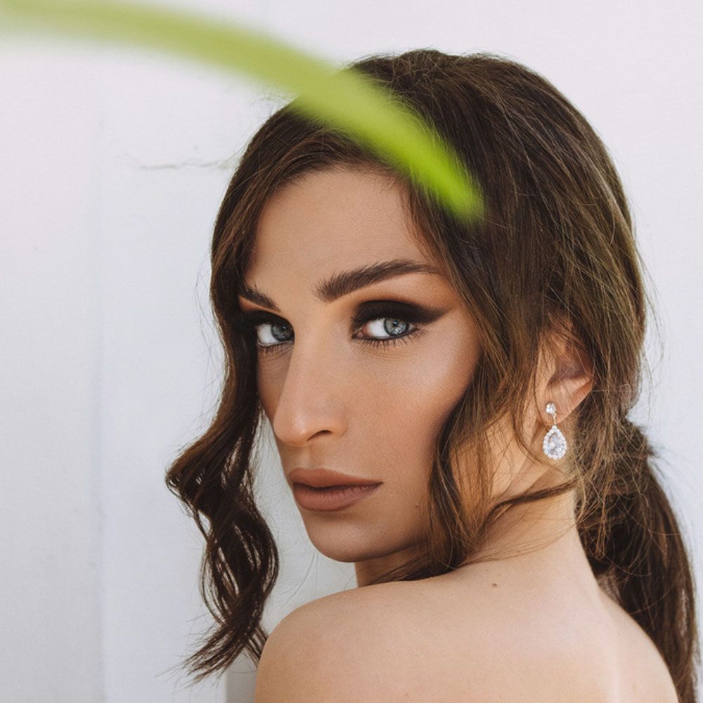 A close up of a woman 's face with a plant in the background