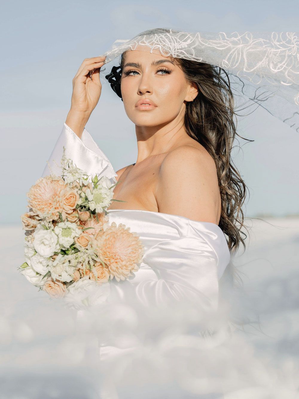 A woman in a white dress and veil is holding a bouquet of flowers.