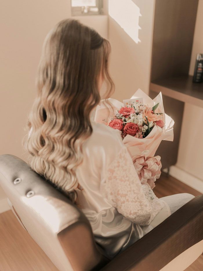 A woman is sitting in a chair holding a bouquet of flowers.