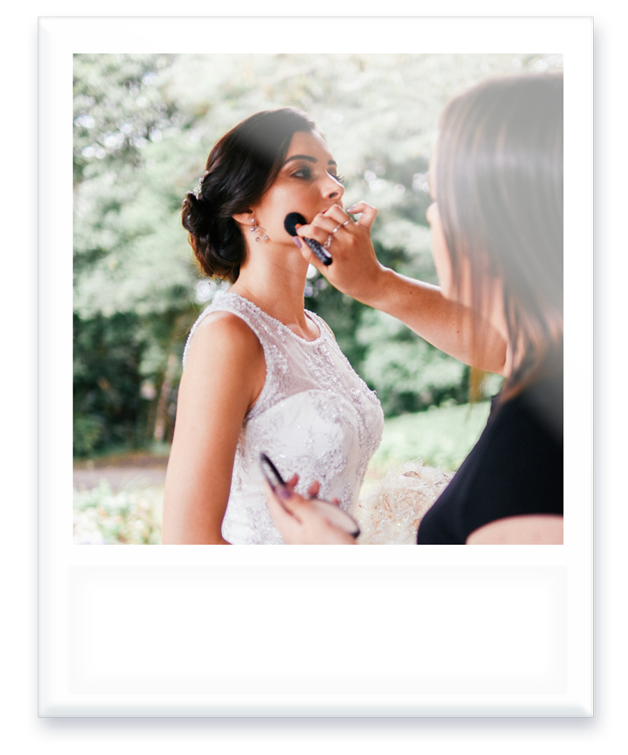 A woman is applying makeup to a bride 's face