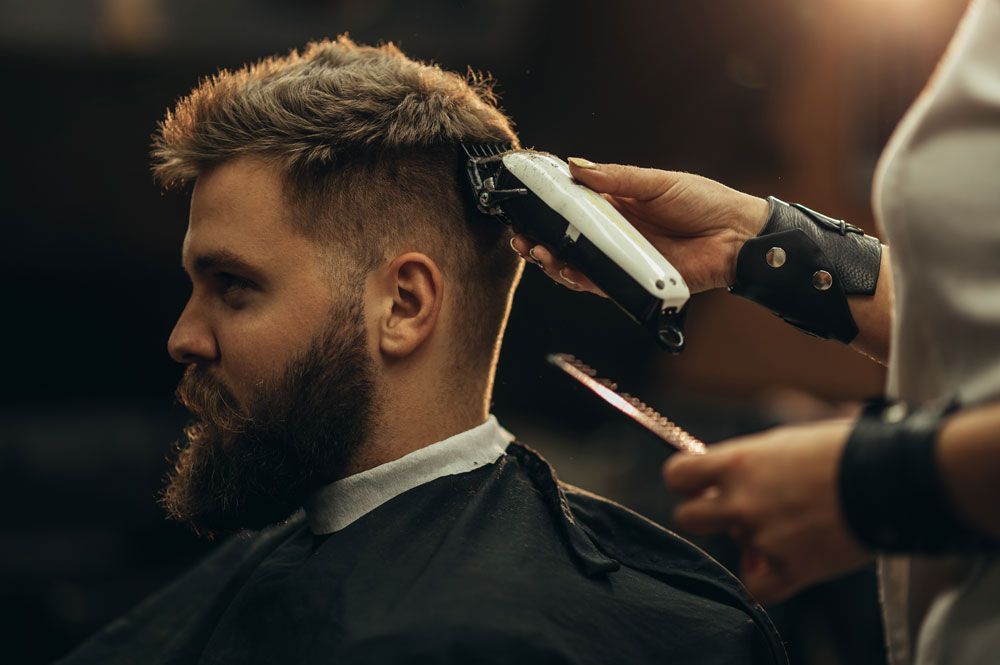 A man with a beard is getting his hair cut by a barber