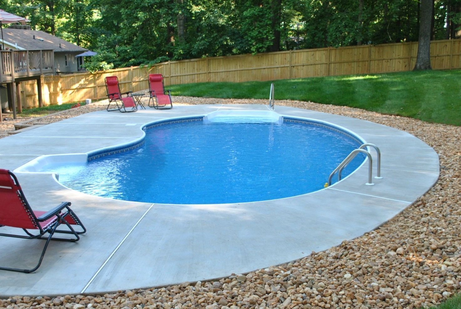 A swimming pool surrounded by rocks and lawn chairs