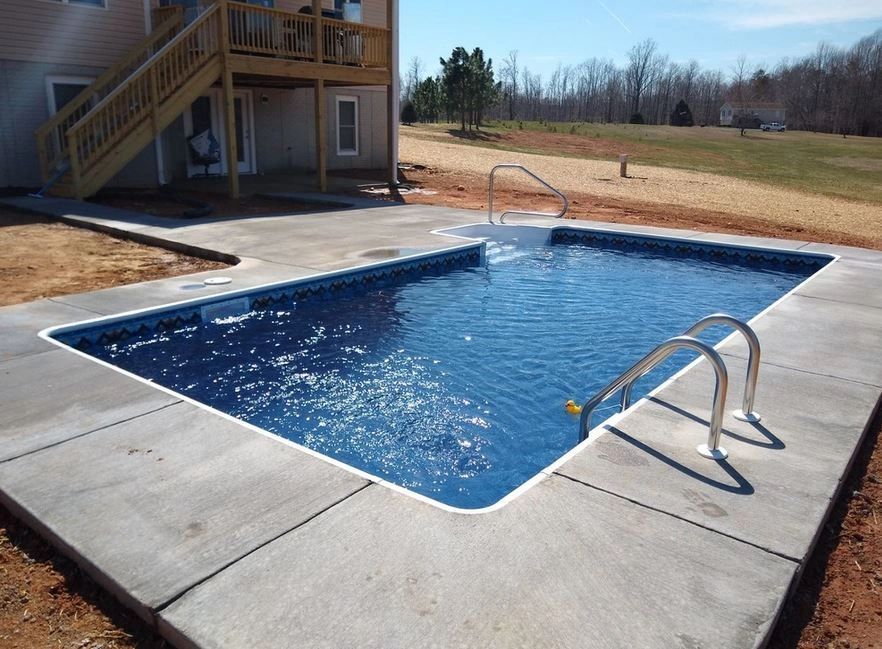 A large swimming pool with stairs leading to it in front of a house