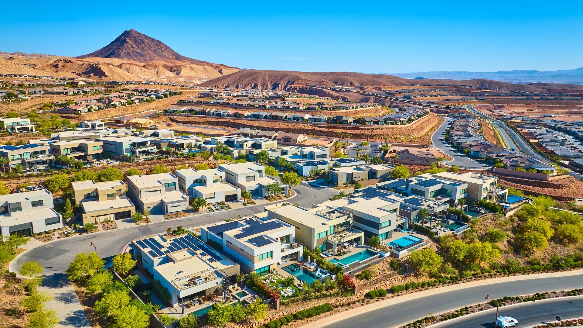 Aerial view of a suburban neighborhood in a desert landscape with modern houses that have solar installed on the roof.