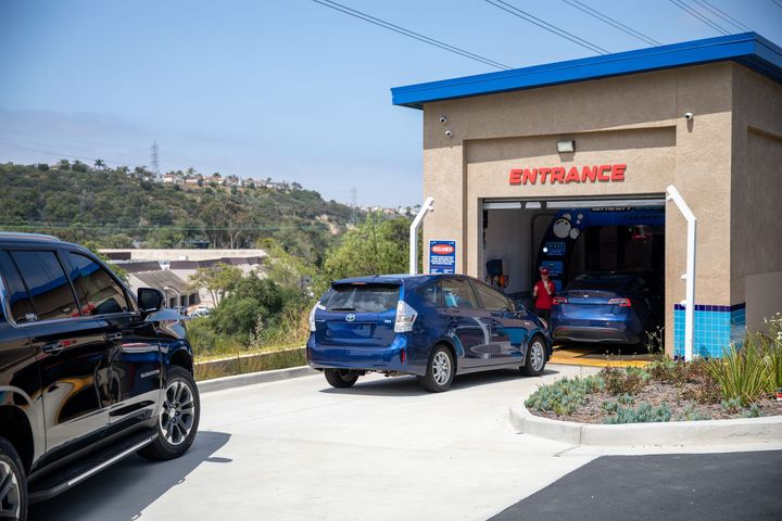Wheely Clean car wash entrance with blue arch and black curtain inside, viewed down a wet tunnel