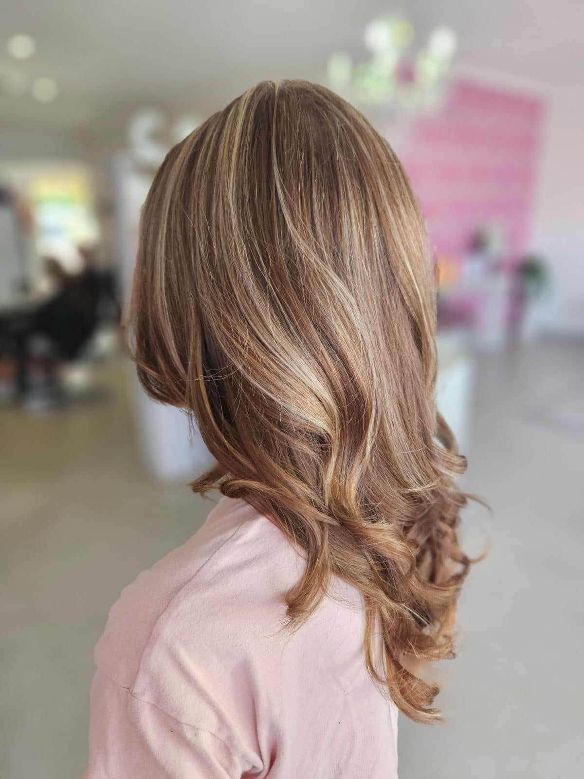 A Woman With Long Brown Hair is Wearing a Pink Shirt — Cosmo Hair & Beauty In Nambour, QLD