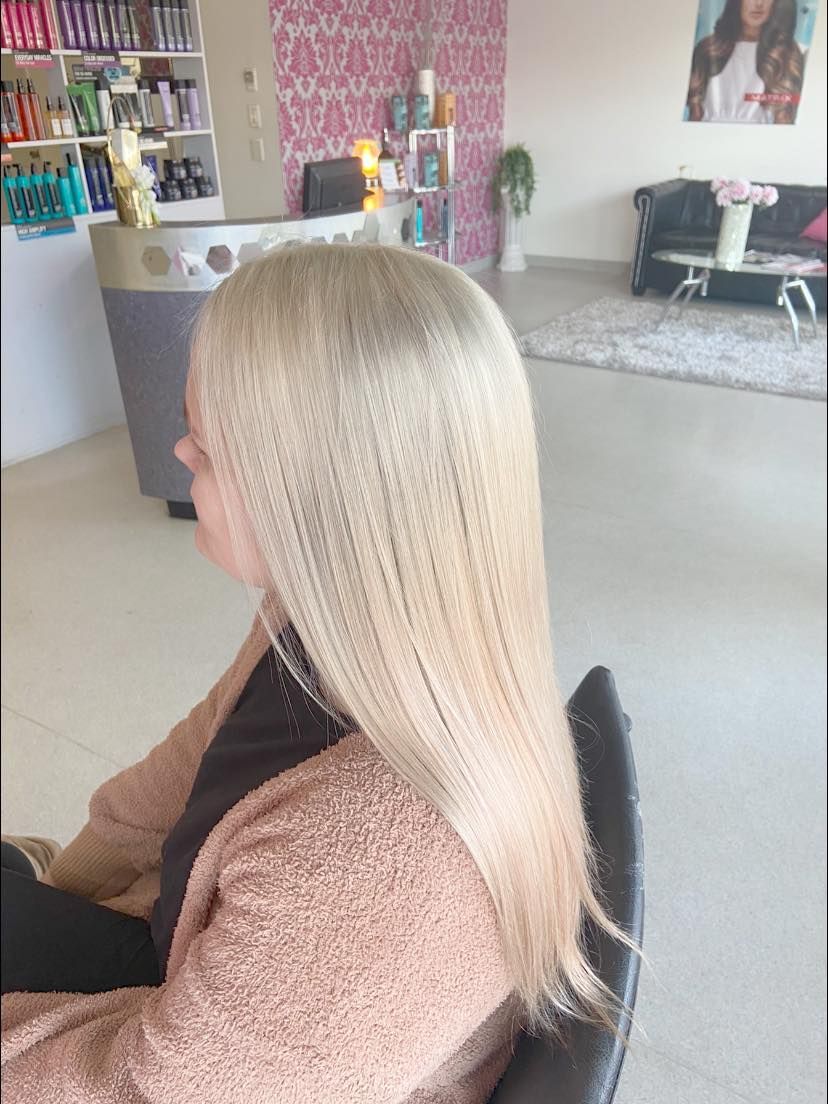 A Woman With Blonde Hair is Standing in a Salon — Cosmo Hair & Beauty In Nambour, QLD