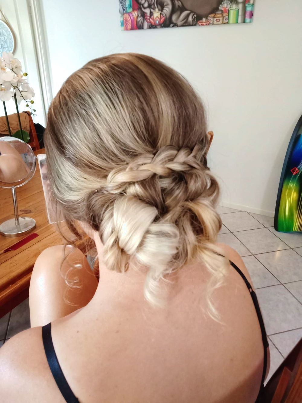 A Woman in a Braided Bun is Sitting in Front of a Mirror — Cosmo Hair & Beauty In Nambour, QLD