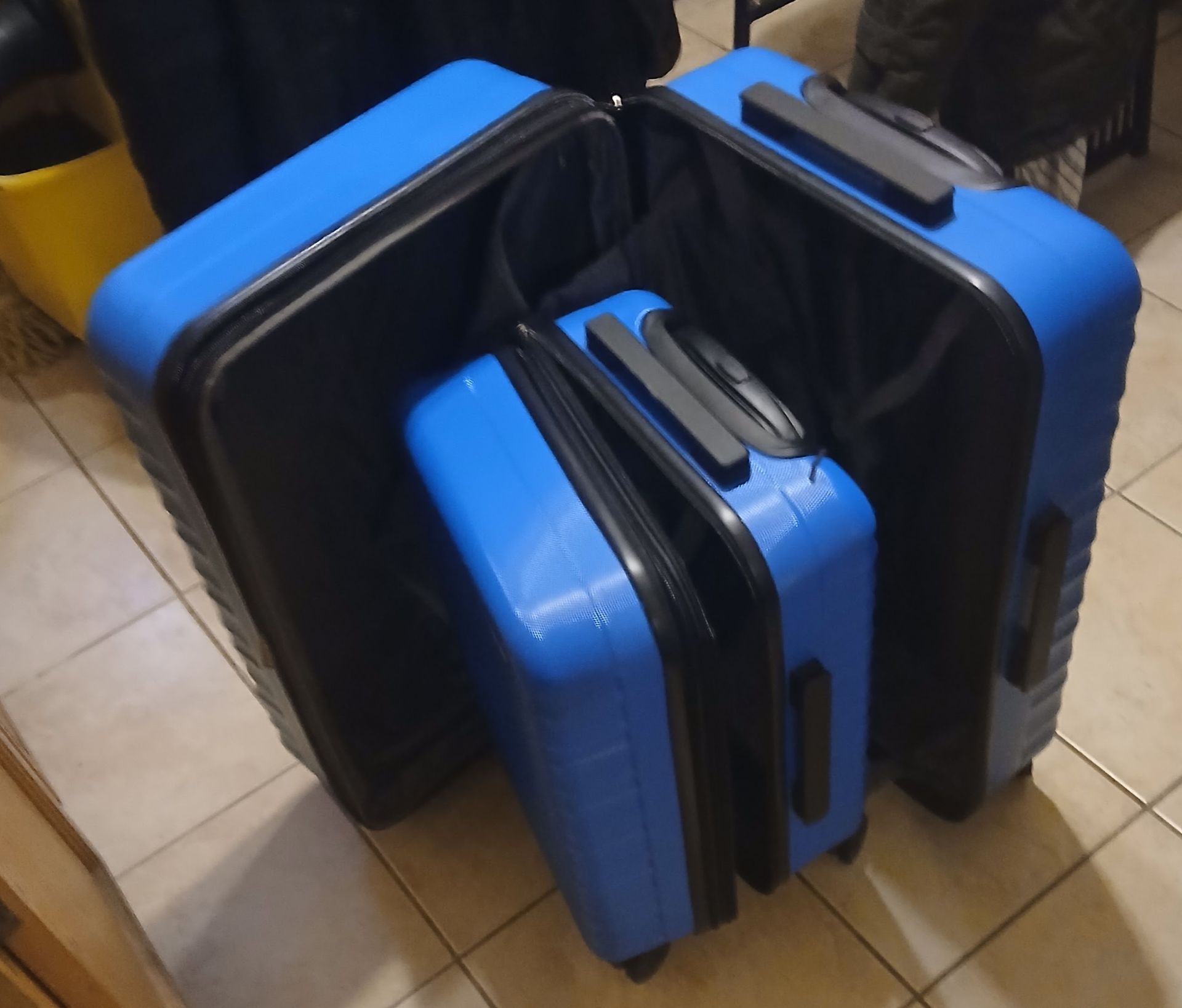 Three blue suitcases, nested inside each other, on a tiled floor.