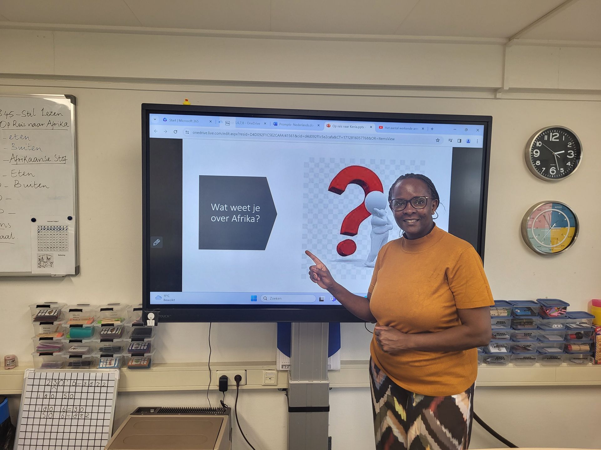A woman is pointing at a screen with a question mark graphic in a classroom.