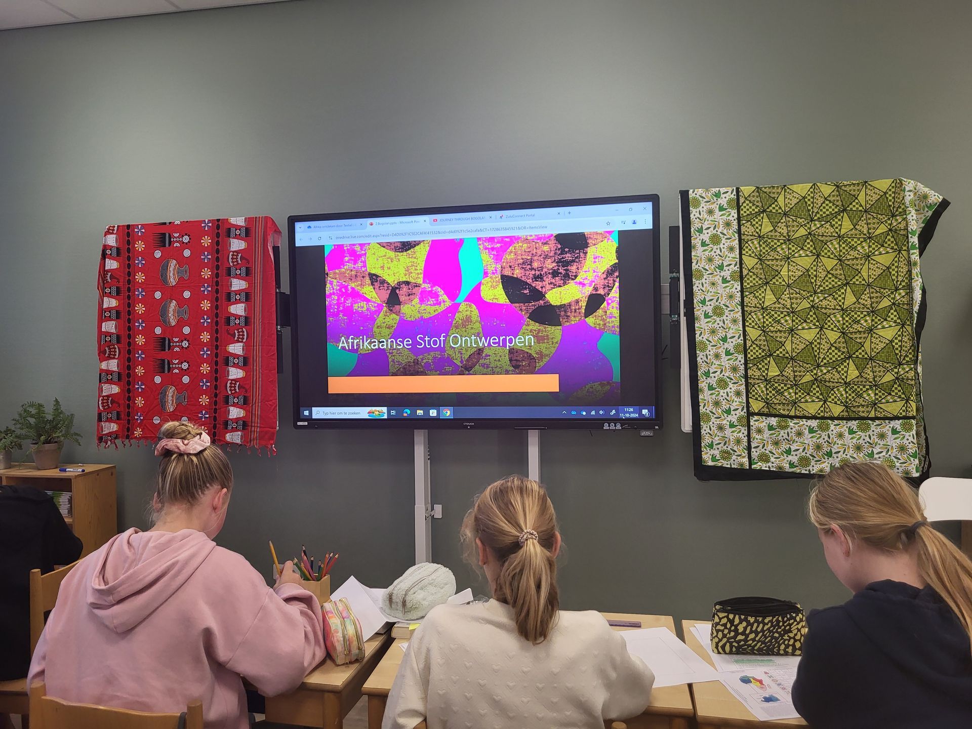 Students at desks watching a presentation on a screen, with colorful fabrics on the wall. Discovering Africa in the classroom