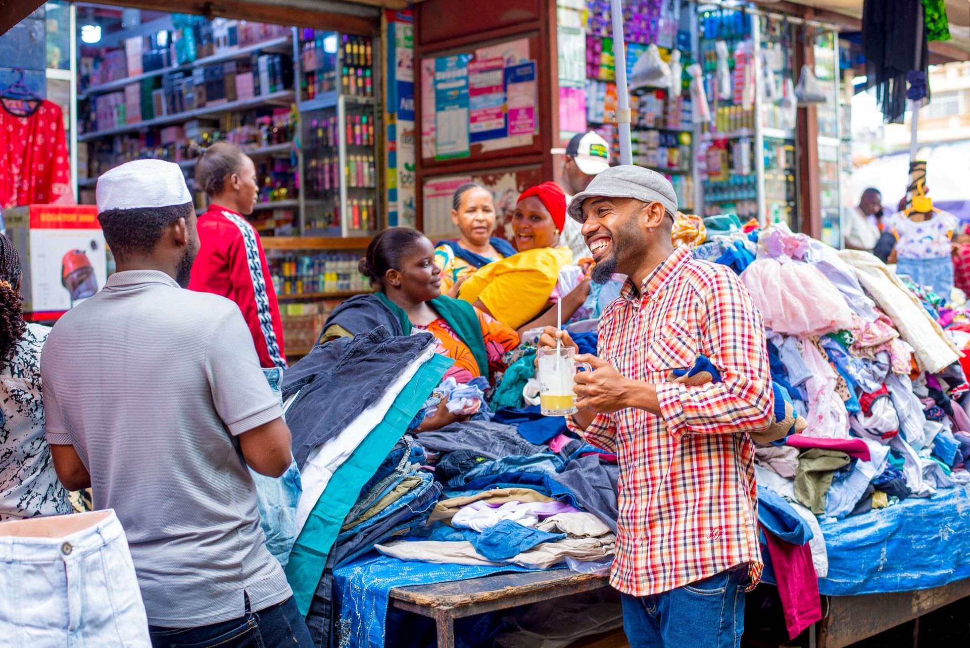 People performing a traditional dance outdoors, near a fence and drums, with mountains in the background.