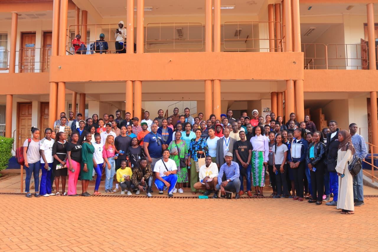 Three people wearing aprons in a kitchen prepare food at a table; a woman in the background.  Discovering Africa in the classroom