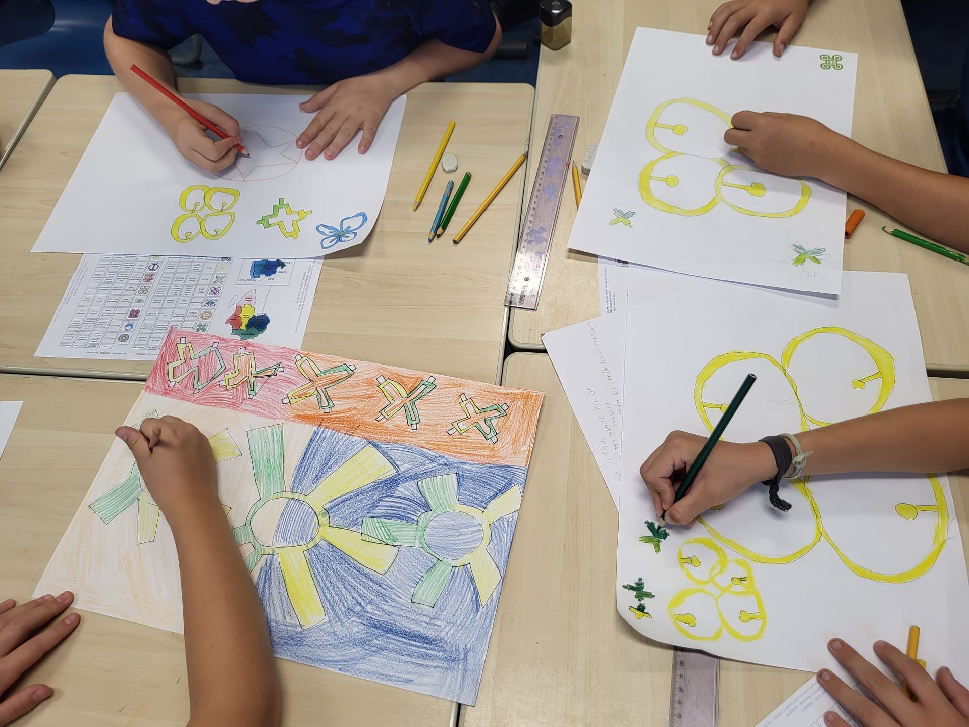 Students are drawing with colored pencils on paper at a table.  Discovering Africa in the classroom