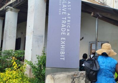Sign for the East African Slave Trade Exhibit; a person in a blue dress enters the building.Educultural Travel