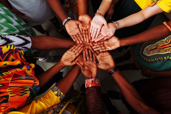 Hands of diverse people in a circle, palms touching, symbolizing unity and cooperation.