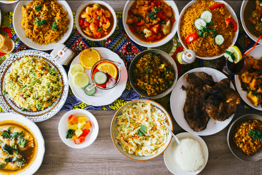 Assortment of diverse dishes, including rice, stews, and sides, arranged on a table.