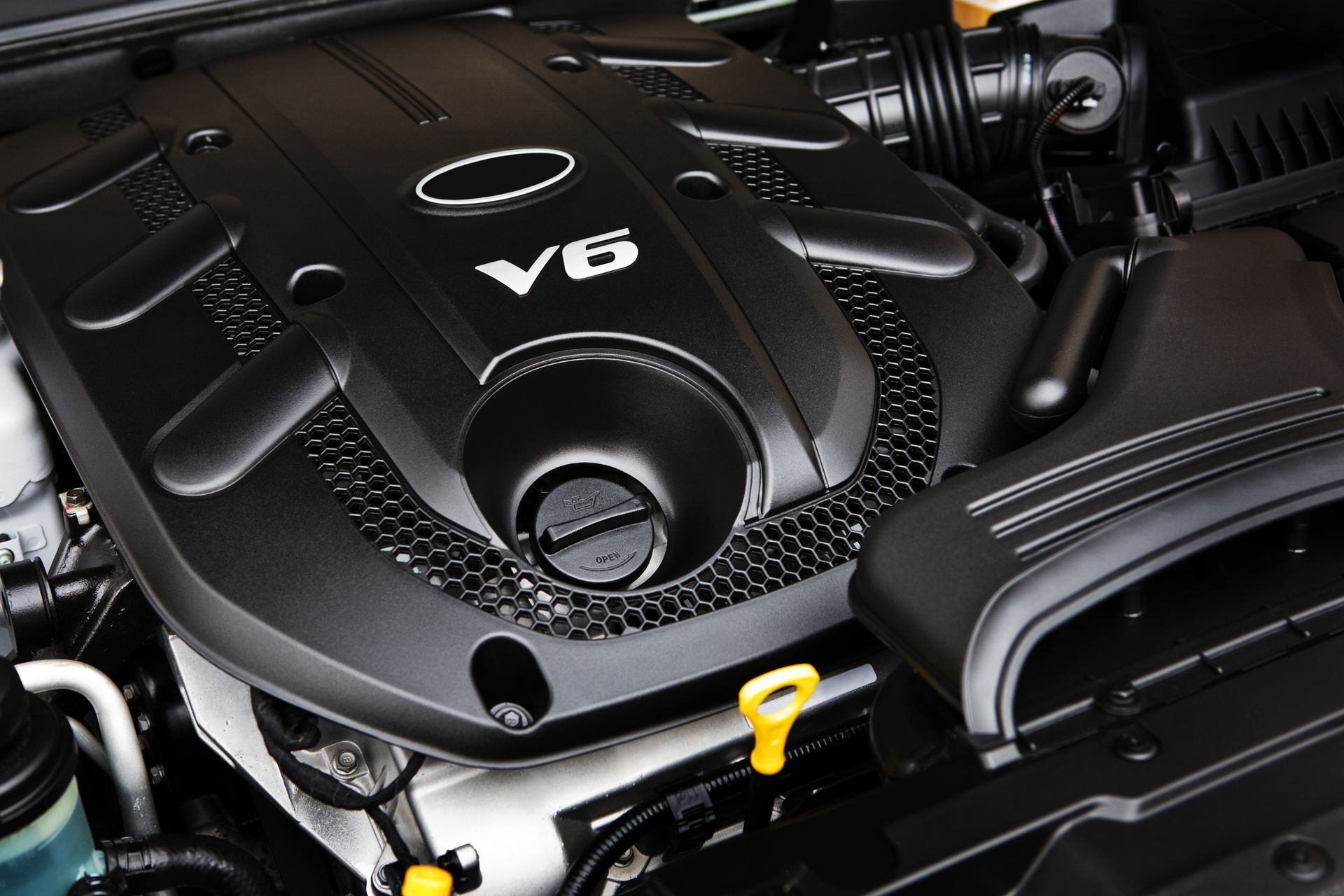 Black V6 engine in a vehicle, with a yellow dipstick and black components.